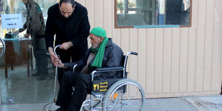 خادمان با صندلی چرخدار در خدمت سالمندان در حرم مطهر هستند